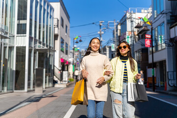 Happy Asian woman friends walking and shopping together at Shibuya district, Tokyo, Japan in...