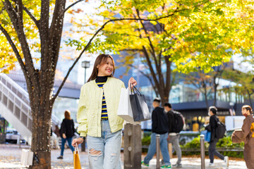 Happy Asian woman tourist holding shopping bag walking at Shibuya district, Tokyo, Japan....