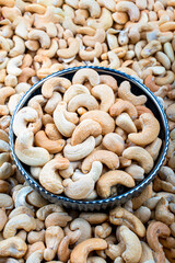 Bowl of Salted Cashews on a Pile of Unsalted Nuts, A vibrant image featuring a bowl of salted cashews placed centrally on a backdrop of unsalted cashew nuts.