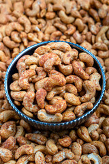 Bowl of  Pepper Cashews on a Pile of Unsalted Nuts, A vibrant image featuring a bowl of Pepper cashews placed centrally on a backdrop of unsalted cashew nuts. Perfect for culinary themes and healthy