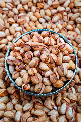 Close-Up of Barbeque Pistachios in a Decorative Bowl, A detailed close-up image of barbeque-flavored pistachios in a stylish bowl, surrounded by a heap of similar nuts.