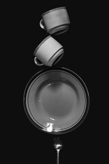 still life photography of pile of plates and cups, pile of cutlery isolated black background