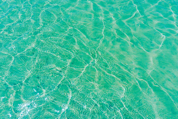 Sun lights shadow in wavy water on abstract sand background