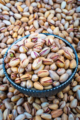 Salted Pistachios In A Bowl With Nuts Background, A bowl full of salted pistachios set against a backdrop of scattered pistachios, showcasing a healthy, nutritious snack.