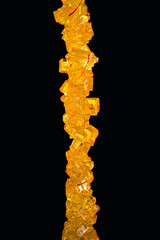 Close-Up of Saffron Rock Candy  , Detailed image of saffron rock candy on a stick against a black...