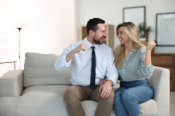 Blurred view of happy couple sitting on sofa at home, space for text