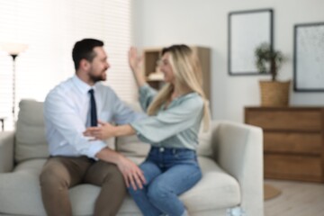 Blurred view of happy couple sitting on sofa at home