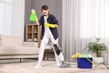 Happy young housewife with spray bottle having fun while cleaning carpet at home