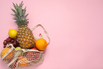 String bag with fresh fruits on pink background, top view. Space for text