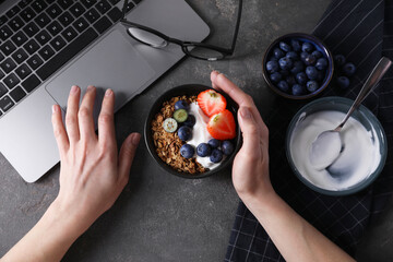 Woman with tasty granola at workplace, top view