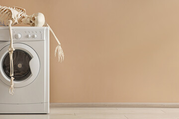 Waiting concept. Human skeleton lying on washing machine near beige wall indoors, space for text