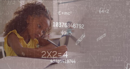 Image of maths calculations and data over biracial schoolgirl concentrating at desk in class