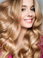 Beautiful blonde woman with curly volume hairstyle, long luxurious hair and beauty makeup,...