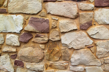 Wall with stones of various shapes and colours textured abstract background