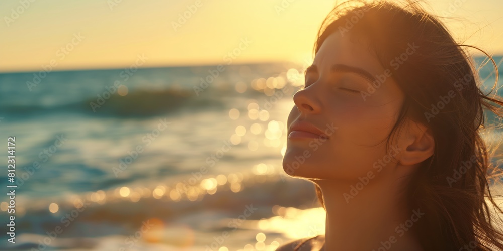 Wall mural Silhouette of a woman's back as she looks at a scenic beach sunset, her hair blowing in the wind - Wall murals