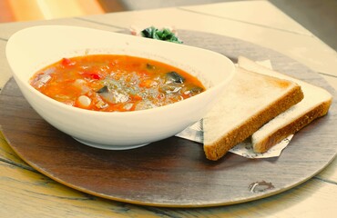 minestrone soup with toast on wooden plate