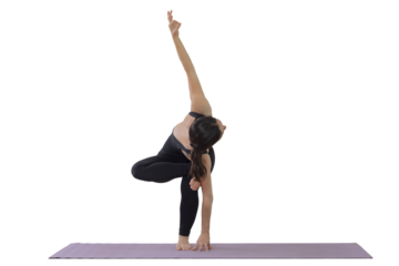Woman practicing yoga in a studio makes a standing pose, with a namaste sign on the wall