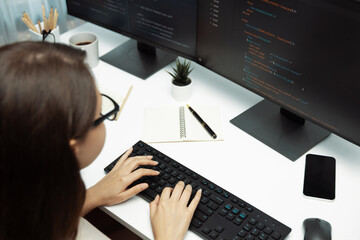 IT developer woman coding on laptop screen at back side view, creating social media website system...