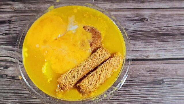A sweet mixture dessert of rice pudding, milk cream qishta, basbousa, konafa, ice cream, whipped cream, mango juice, pieces, milk and sugar, honey sugary syrup, sweet high calories bomb dessert mix