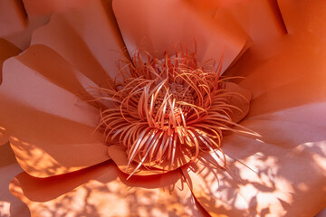 A paper flower with orange petals and a brown stem