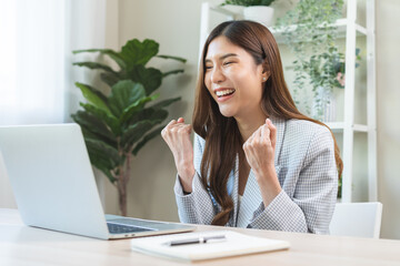 Happy cheerful asian young woman celebrate online looking at laptop computer screen, receive good...