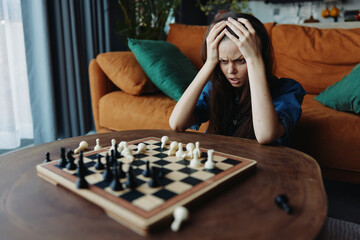 Woman contemplating her next move during a intense chess match, sitting on a couch with a chess...