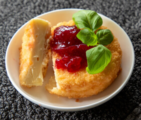 Crumbed camembert in breadcrumbs with basil leaves.