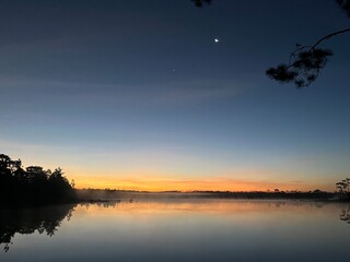A beautiful lake with a sky full of stars and a crescent moon