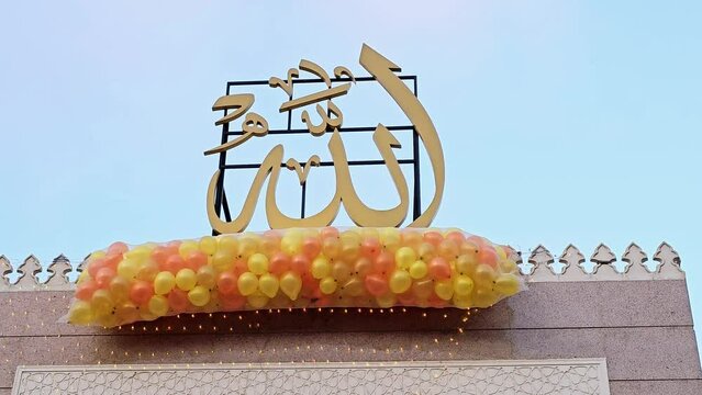 Translation of Arabic text (Allah, The God), festive and celebrations outside a mosque in Cairo with tens of balloons held in the mosque's roof beside the minaret to be thrown for kids for Feast