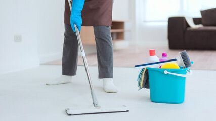 Maid using mop with bucket plastic of cleaner equipment to mopping cleanup floor in living room