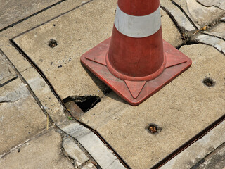 cement tile covering the manhole cover is damaged and has a hole. Use traffic cones to warn road...