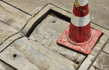 manhole cover is damaged and collapsed. Use traffic cones to warn road users to be careful. closeup