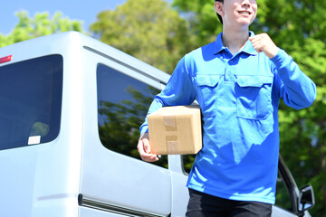 屋外で荷物を運ぶ配送ドライバーの男性