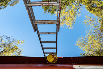 Stockholm, Sweden An underside view of a metal ladder and a can of red paint with a brush.