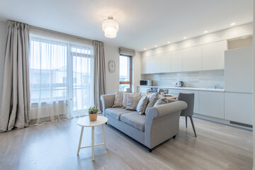 Living Room and Kitchen. Sofa. Composition of Kitchen and Living Room Interior with Gray Sofa, Dinnig Table, Curtains, Accessories, Widows. Home decor. Watch on the Wall.
