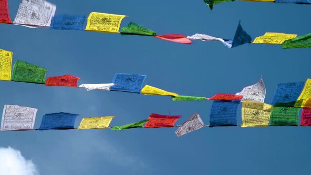 Colorful prayer flags against a blue sky at a Buddhist temple in northern India