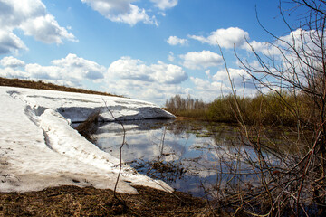 On a clear spring day near a small lake with melting snow