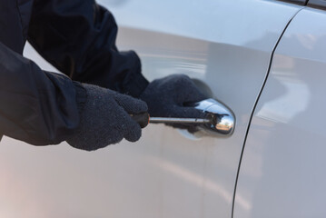 Close-up, Man dressed in a black holding screwdriver to break the lock and steal a vehicle on the...