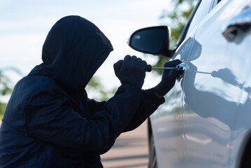 Close-up, Man dressed in a black holding screwdriver to break the lock and steal a vehicle on the...