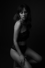 Fototapeta premium Studio portrait of a beautiful caucasian woman in her thirties wearing black lace underwear and top. Her long dark hair is blowing in the wind. This is a moody portrait. 