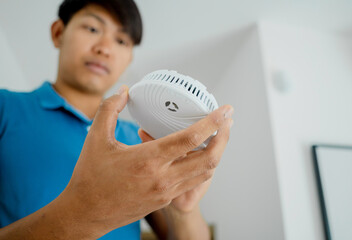 Technician installing fire safety detector in a modern apartment