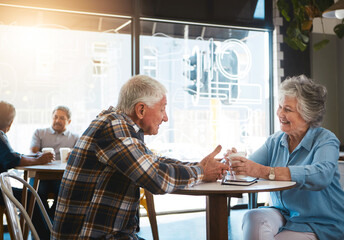 Obraz premium Senior couple, talking and happy in cafe for date with conversation, drinking tea or communication. Elderly, people and discussion in coffee shop with smile for bonding, retirement or relax with care