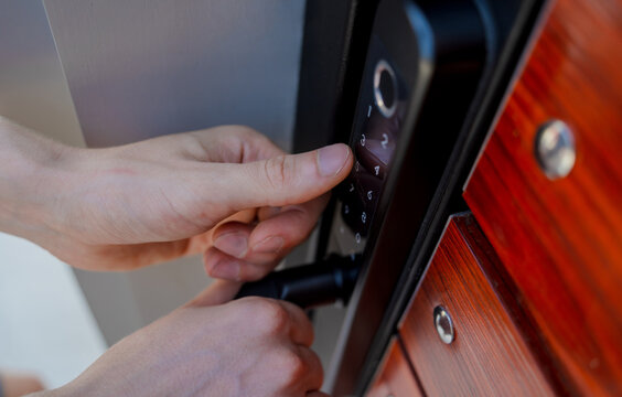 A technician installs a modern smart door lock on the wood door