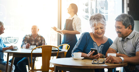 Elderly couple, restaurant and table together for bonding, smartphone and talking or browsing and...
