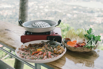 Thai traditional barbecue pork on grilled aluminium pan with soup canal (Moo Krata), barbecue party on wooden table with fingers handle chopsticks