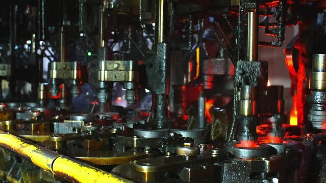 Glass factory, production of glass containers. Molten glass is blown into molds. Robotics in industry. Modern technologies, robotic machines produce products. Technological work at the plant.