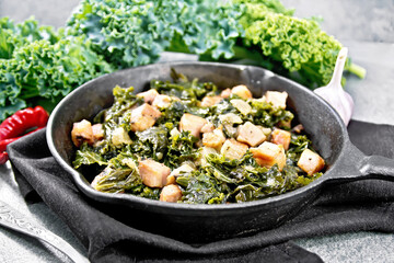 Kale cabbage with bacon in pan on stone table