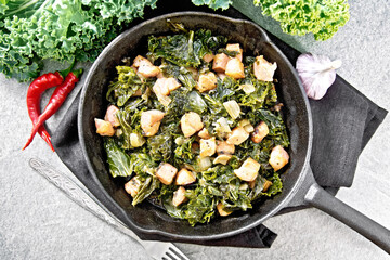 Kale cabbage with bacon in pan on stone top