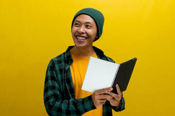 A young Asian student, dressed in a beanie hat and casual shirt, gazes at an empty space, pondering education and the future while holding an open book, standing against yellow background.