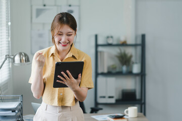 Confident young professional asian woman using tablet in modern office.